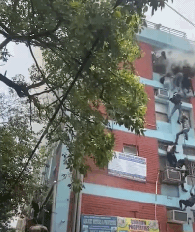 印度首都德里一家补习中心失火，学生抓着电线从窗户滑下逃生。 （撷自The Indian Express影片）