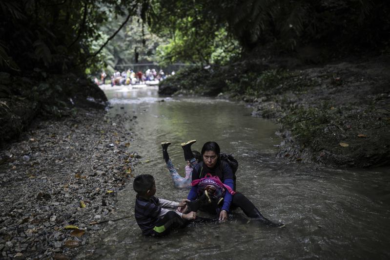 從南方的哥倫比亞走到北邊的巴拿馬之間的達連隘口，是目前最熱門的偷渡途徑，雖然危險，但漸成有組織、沿途有服務的路線。圖為一位委內瑞拉的母親帶著子女，眼神堅毅，坐在溪中休息，目的地是美國。(美聯社)