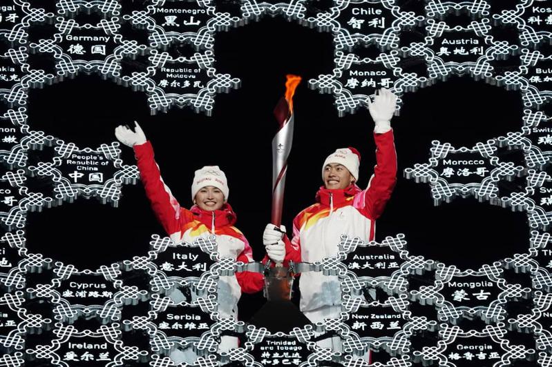  冬奧火炬台別出心裁，台面由各個國家名牌組成。最後一棒火炬手由迪妮格爾依拉木江(左)和趙嘉文(右)完成傳遞。(美聯社)