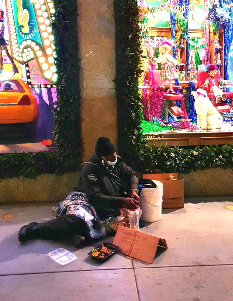 游民坐在曼哈顿中城的圣诞节橱窗前，向路人乞讨。(记者王彩鹂／摄影)