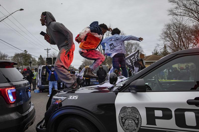 明尼苏达州非裔佛洛伊德之死事发地点不远处，11日发生一名男子因交通违规遭拦检而被员警开枪，最后撞车死亡。 图为案发后民众跳上警车抗议。 (美联社)