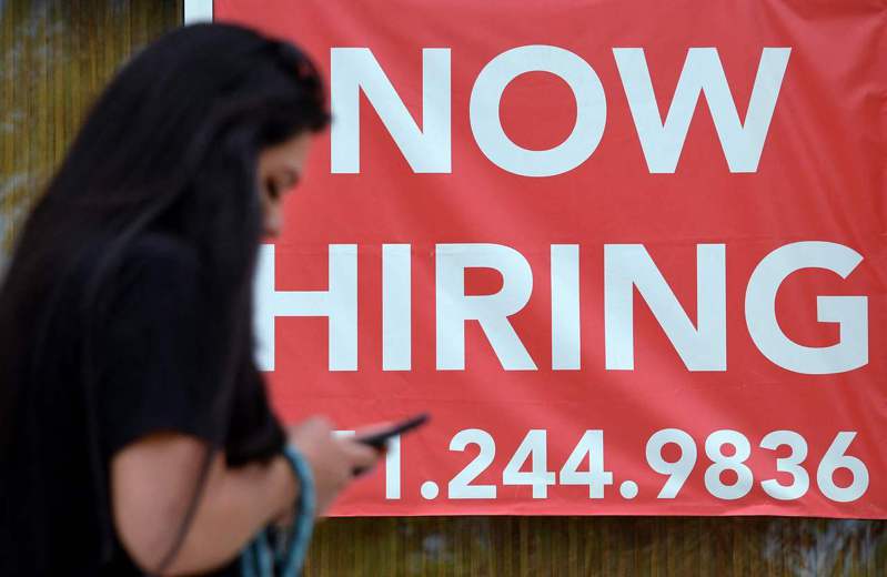美國銀行民調顯示 ，多達七成工薪階層稱他們的薪資趕不上通膨上漲速度。圖為維吉尼亞州阿靈頓市一名婦女走過一個「正在招人」的招牌。(Getty Images)