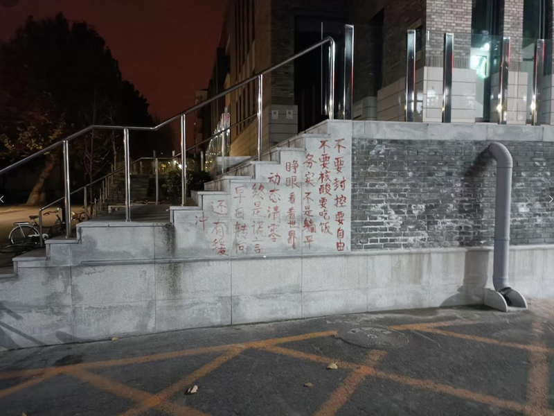 北京大學爆發抗議封控的示威活動，餐廳附近的牆壁上出現紅色塗鴉文字，寫著示威字句。（推特圖片）