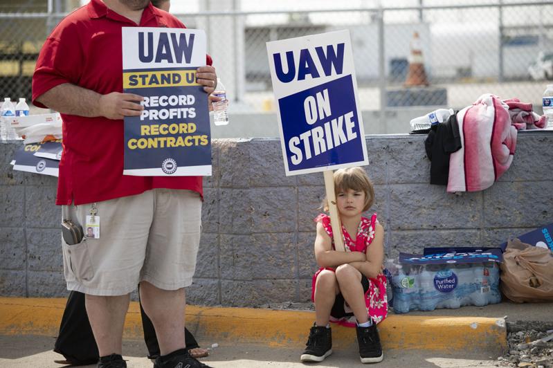 密西根州的福特車廠工人在罷工時，一名小女孩也拿罷工的標語牌。（Getty Images）