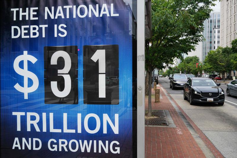 國債已達創紀錄的33兆元，增加速度驚人。圖為今年5月中旬華府海報上的國債數字還是31兆元。(Getty Images)