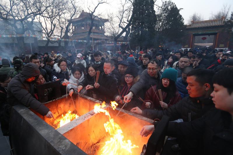 大批市民趕在新年湧進雍和宮燒頭炷香祈福，其中不乏年輕人。（中新社）