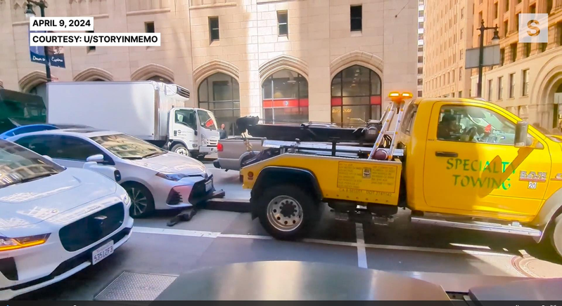 一輛拖車9日試圖在舊金山市中心拖走一輛有人駕駛的汽車。（網路影片截圖）